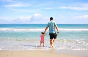 Padre e hija caminando al borde de la playa